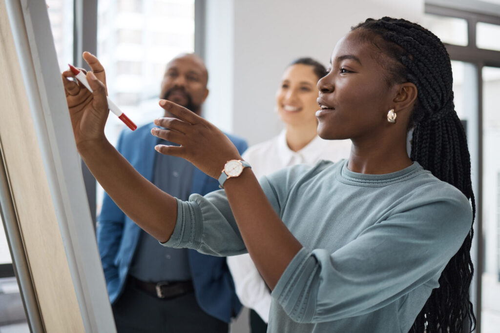 Black woman, business learning and whiteboard writing for company planning with strategy. African female employee, meeting and sales collaboration of staff working with teamwork and workshop idea.